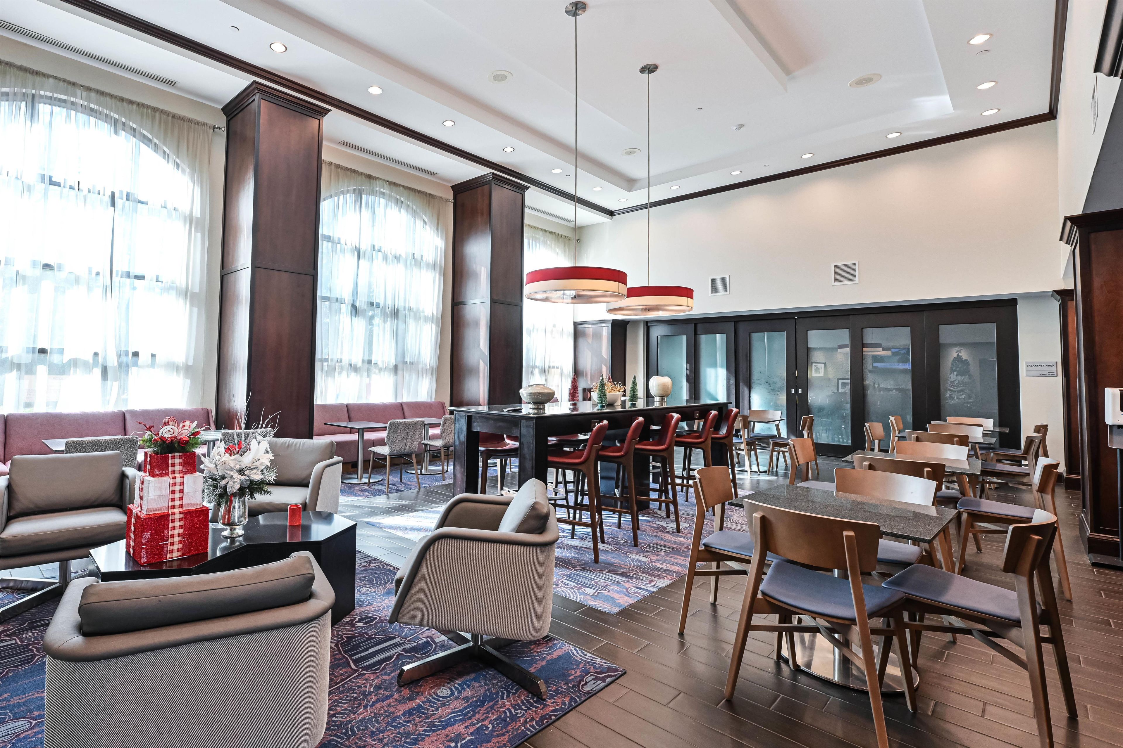 Um saguão de hotel com áreas de estar, um bar e um espaço para o café da manhã.