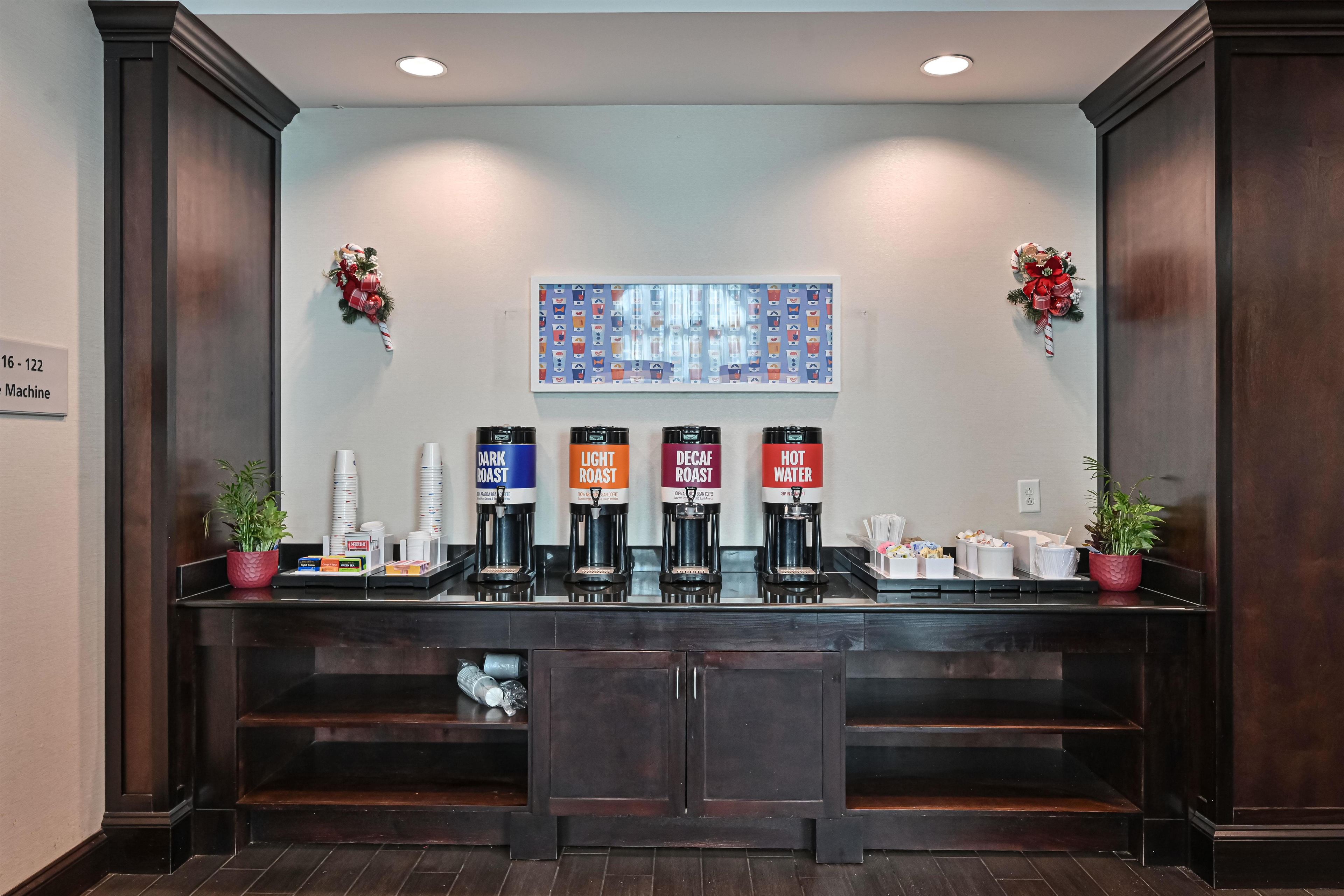 A coffee station with multiple coffee dispensers labeled DARK ROAST, LIGHT ROAST, DECAF ROAST, and HOT WATER.