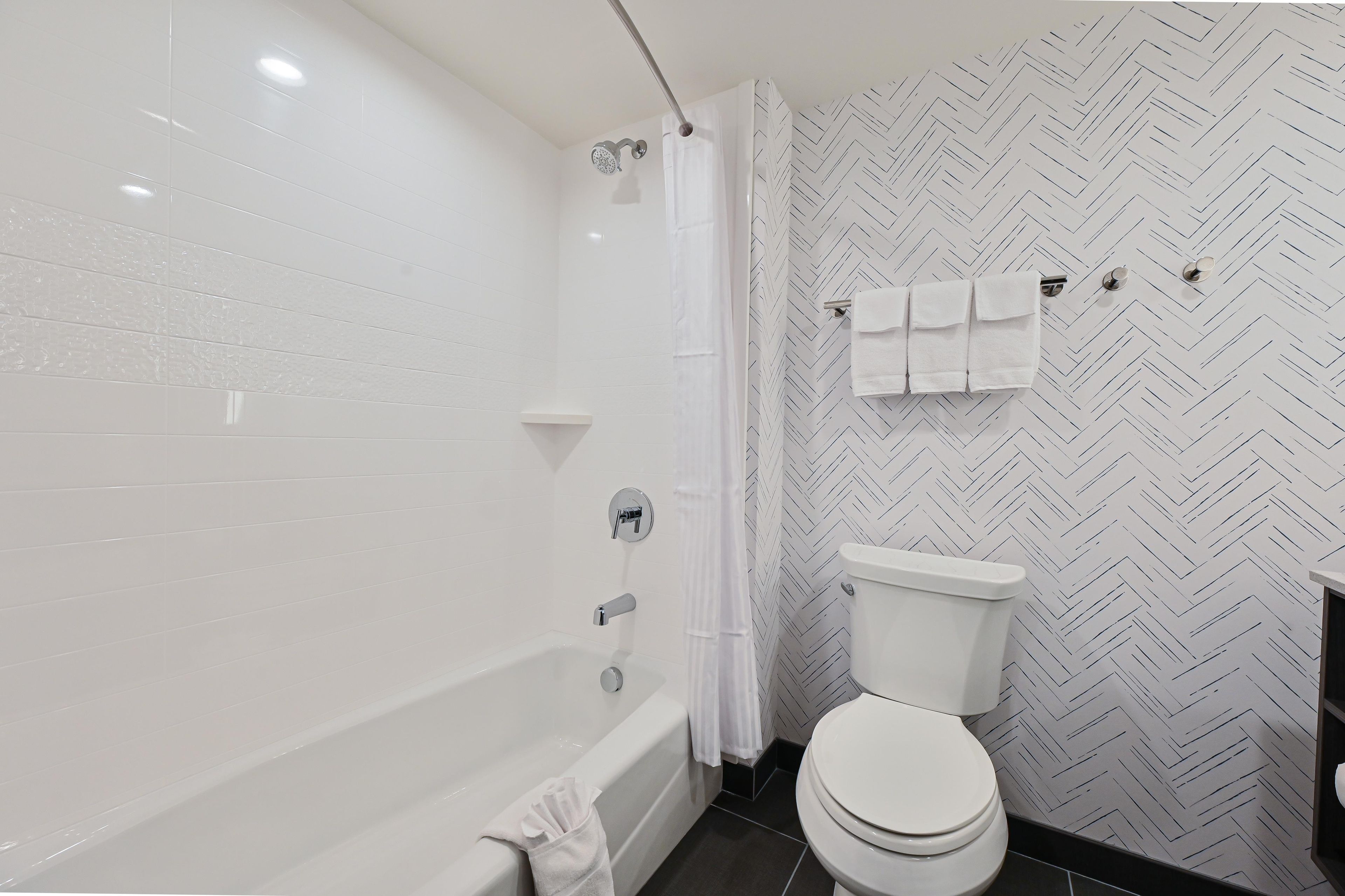 A modern bathroom with a bathtub, toilet, and shower.