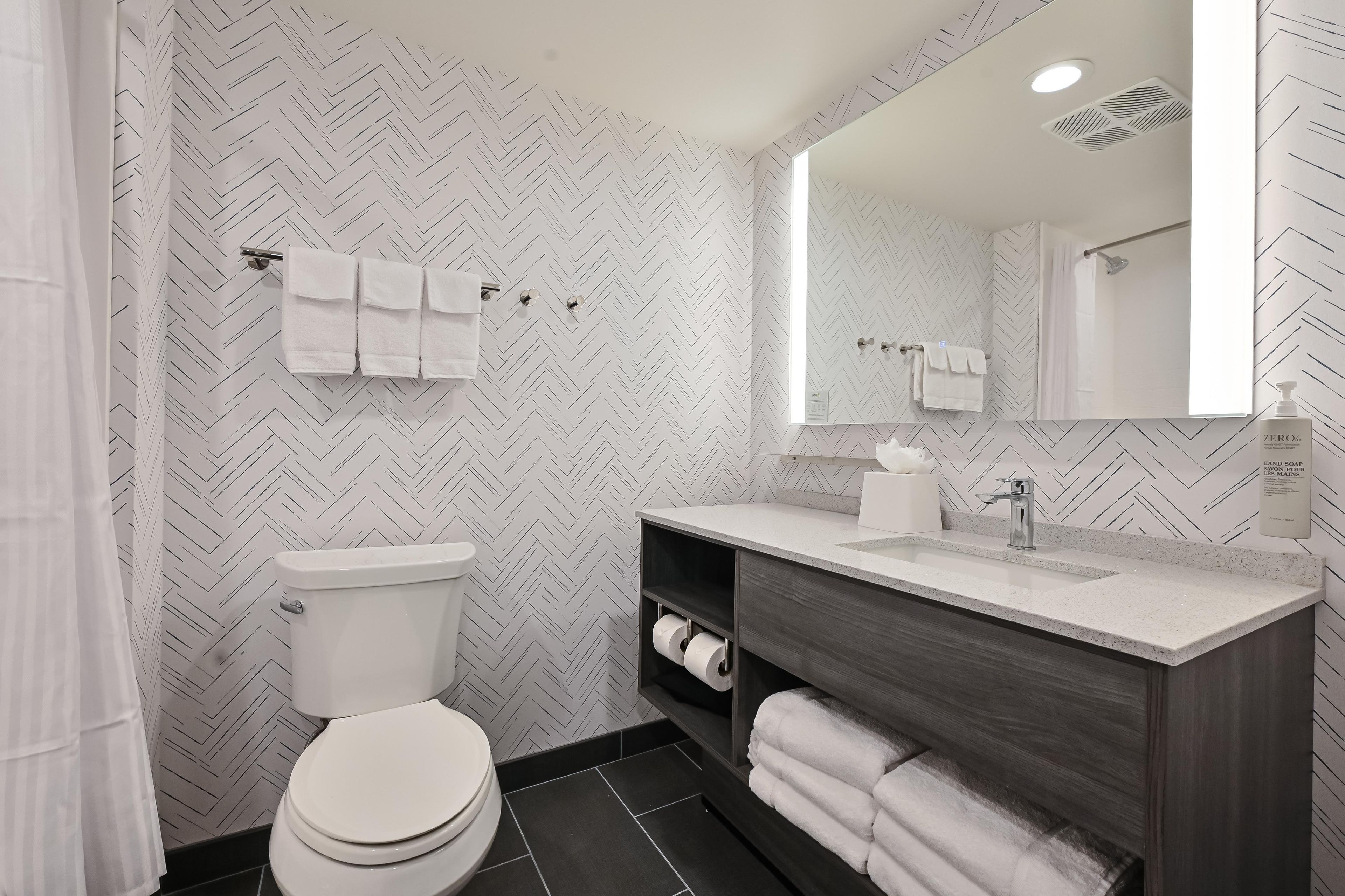 A modern bathroom with a toilet, sink, and mirror.