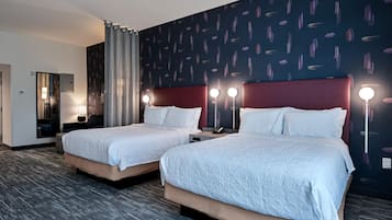 A hotel room with two beds, a mirror, a nightstand, and a wall with a pattern.