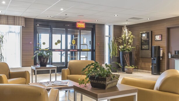 A modern lobby with leather chairs, a reception desk, and potted plants. - Quality Inn Sept-Îles (Uashat)