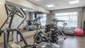 A gym with cardio machines, weights, and a large mirror. - Quality Inn Sept-Îles (Uashat)