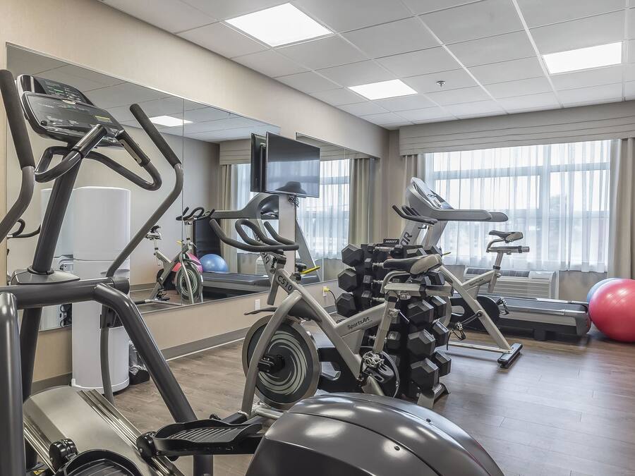Un gimnasio con máquinas de cardio, pesas y un espejo grande.