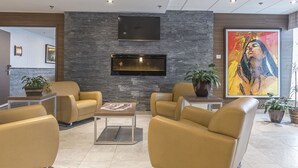 A modern lobby with leather sofas, a fireplace, and a large abstract painting. - Quality Inn Sept-Îles (Uashat)