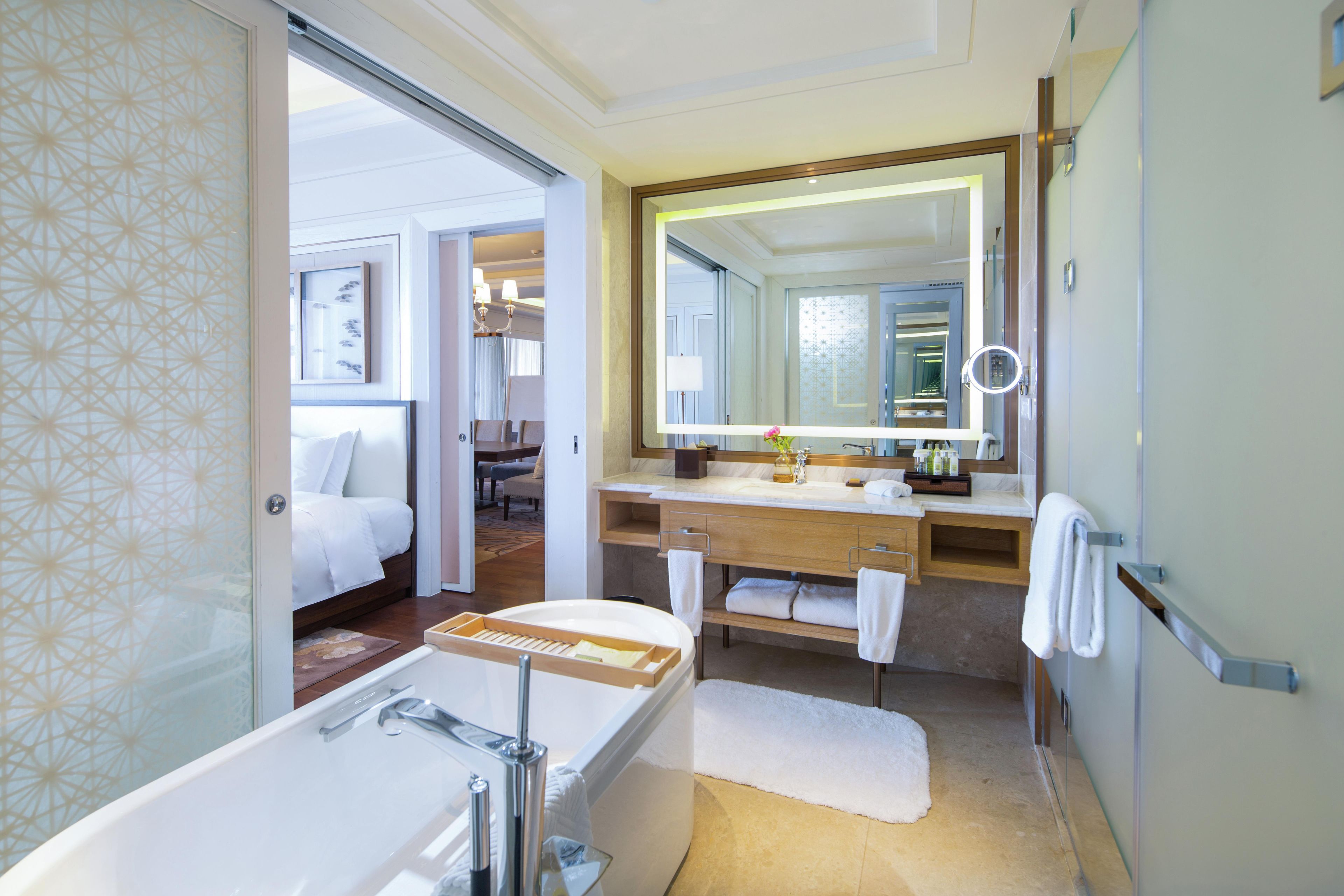 A modern bathroom with a bathtub, a large mirror, and a vanity with a sink.