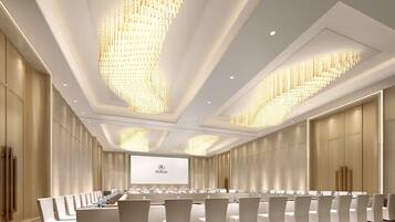 A conference room with a long table, white chairs, and a large screen displaying the Hilton logo.