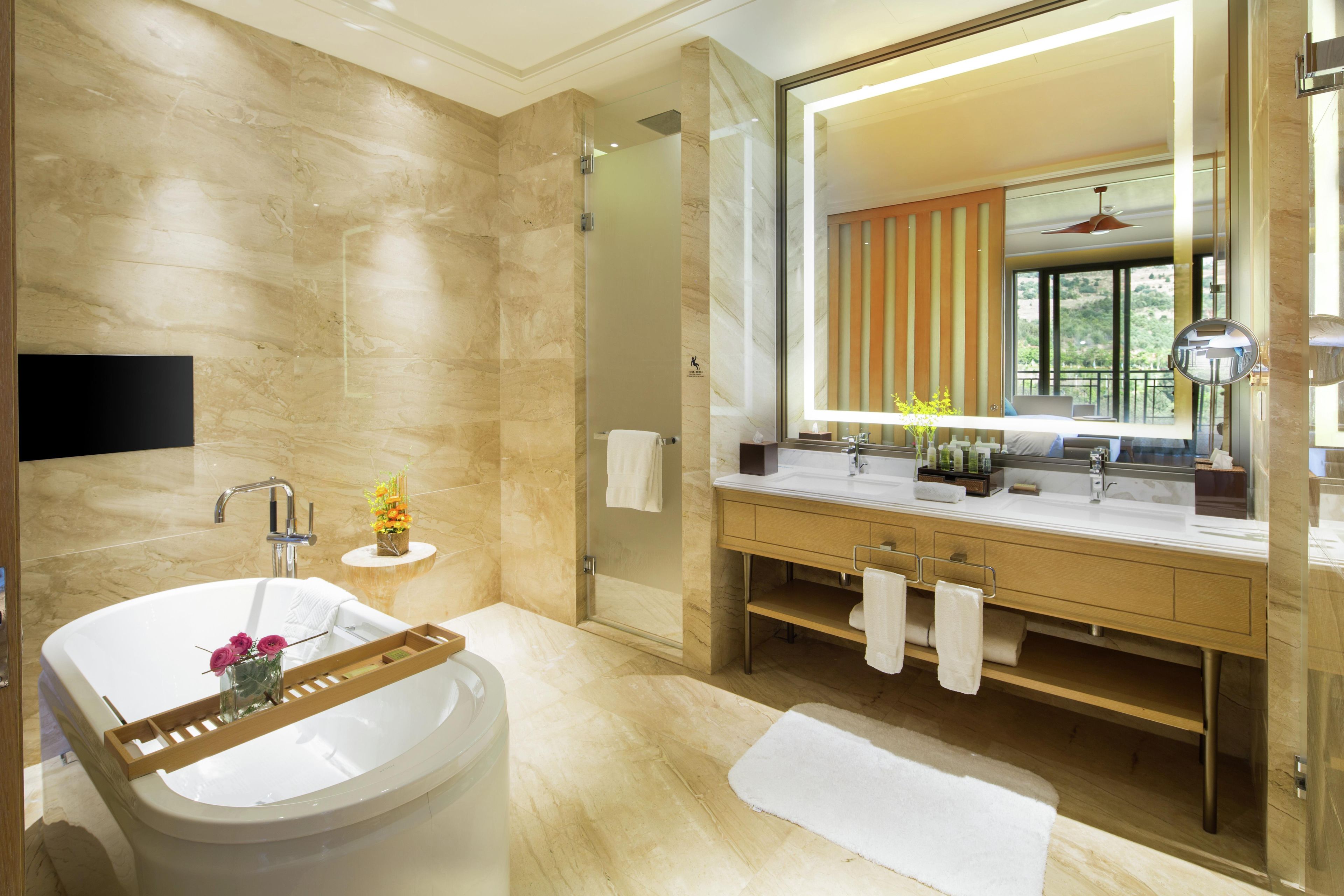 A modern bathroom with a large mirror, a bathtub, and a vanity with a sink and towel rack.