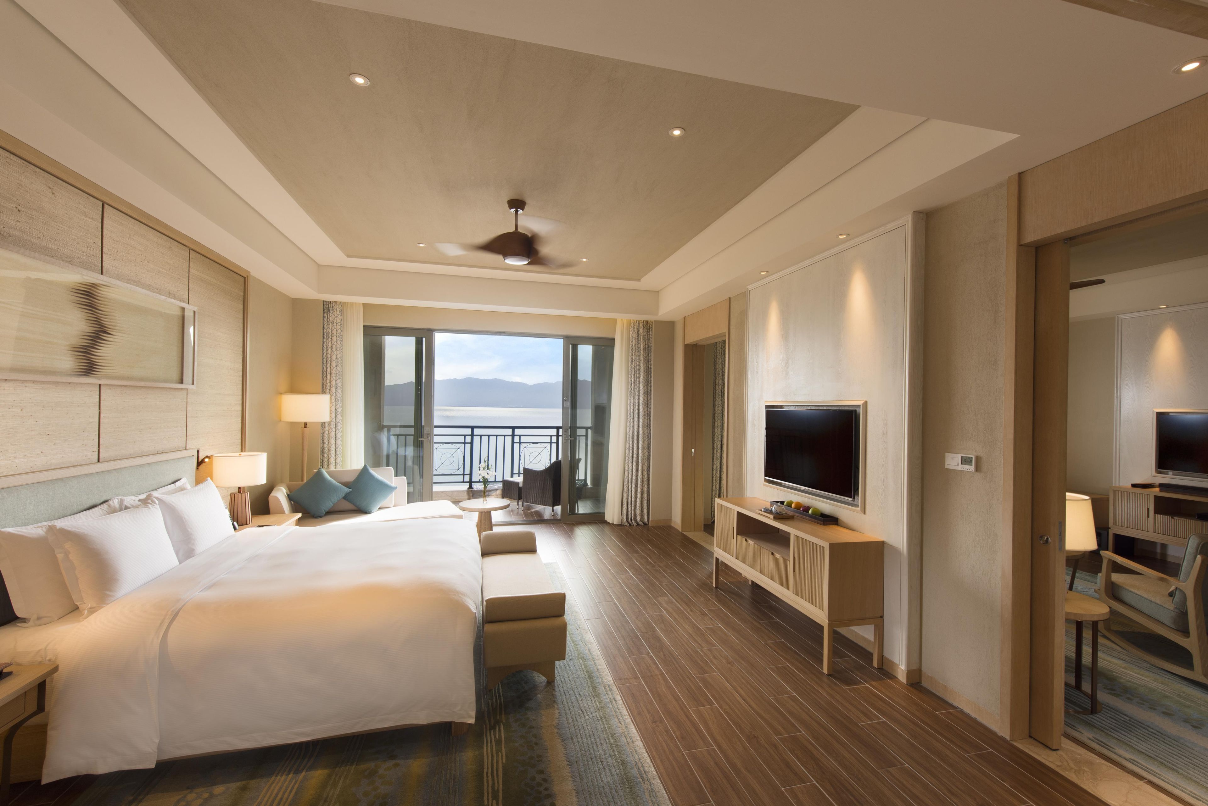 Une chambre d’hôtel dotée d’un grand lit, d’une télévision, d’un coin salon avec vue et d’un balcon.