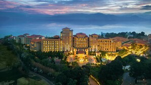 A hotel with multiple buildings, a central courtyard, and a view of the sea. - Hilton Yuxi Fuxian Lake (Yuxi)