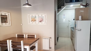A dining area with a wooden table and chairs, a pendant light, and framed pictures on the wall. - San Martin Suites (San Carlos de Bariloche)