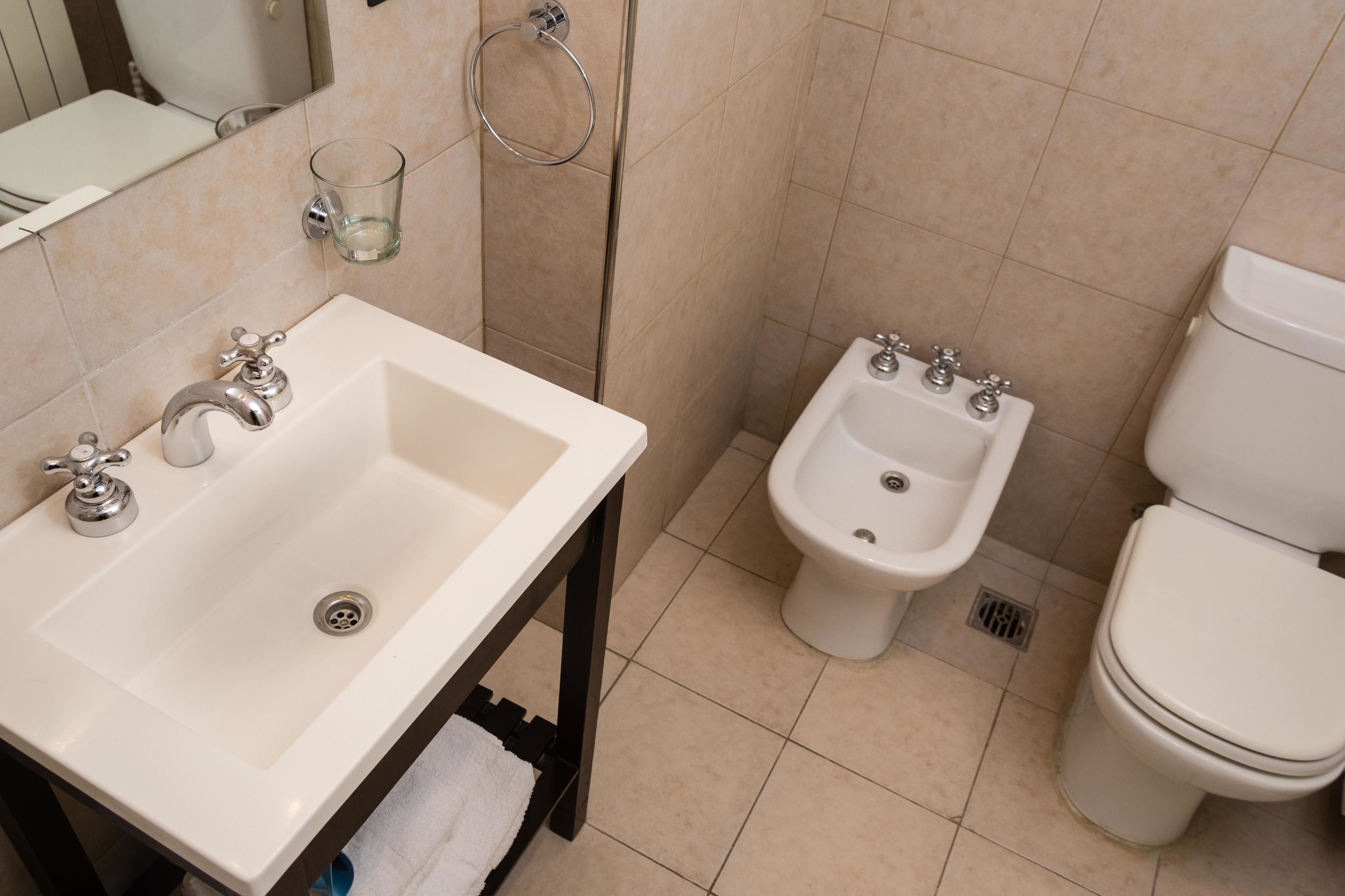 Een badkamer met een wastafel, bidet en toilet.