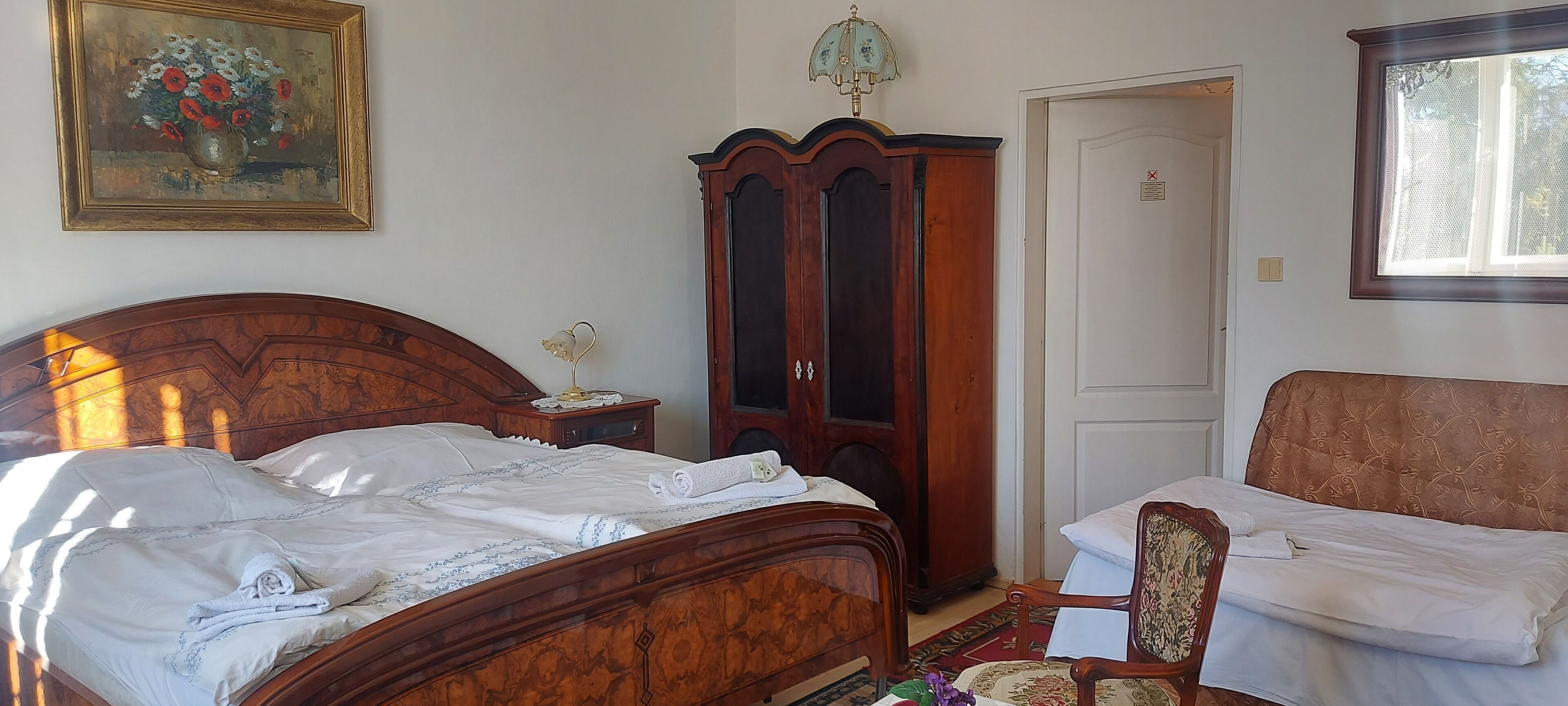 Un dormitorio con una cama de madera, un armario de madera, una silla y un cuadro en la pared.