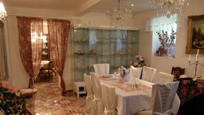 A dining area with a glass display case, white tablecloths, and chairs. - Hotel Garni (Ostrava)