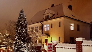 A hotel with a traditional European architectural style, featuring a symmetrical facade, multiple windows, and a snow-covered roof. - Hotel Garni (Ostrava)