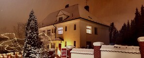 Un hotel de estilo arquitectónico europeo tradicional, con fachada simétrica, numerosas ventanas y tejado cubierto de nieve.