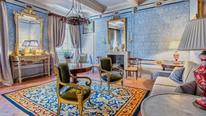 Une chambre luxueuse, dotée d’un grand miroir décoratif, d’une cheminée et d’un canapé moelleux.