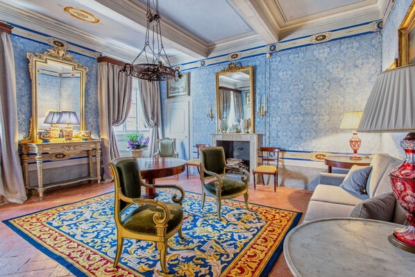 Een luxe kamer met een grote, versierde spiegel, een open haard en een comfortabele bank.