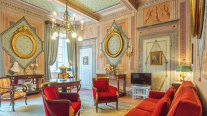 Une chambre luxueuse, agrémentée de décorations raffinées, notamment un lustre, des meubles recouverts de tissu rouge et un téléviseur.