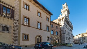Un bâtiment historique doté d’une tour imposante, de fenêtres en arc de cercle et d’une rue pavée.