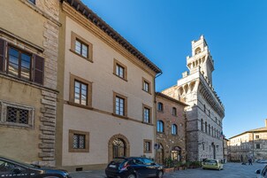 A historic building with a prominent tower, arched windows, and a paved street.