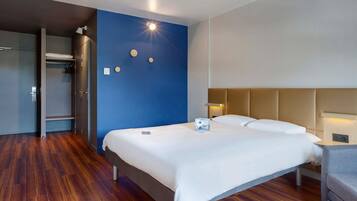 A hotel room with a bed, bedside table, and a wardrobe.