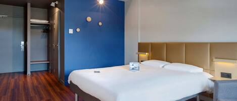 A hotel room with a bed, bedside table, and a wardrobe.