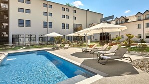 A hotel with a swimming pool, outdoor seating, and a garden area. - Ibis Budget La Roche sur Yon (Mouilleron-le-Captif)