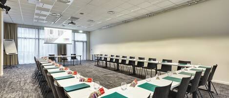 A conference room with a long table, chairs, a projector, and a screen.