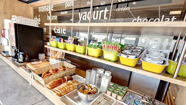 A breakfast bar with various food items and beverages, including bread, pastries, and yogurt. - Ibis Budget La Roche sur Yon (Mouilleron-le-Captif)