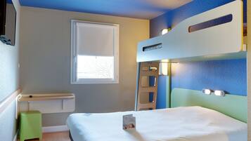 A room with a bunk bed, a small stool, a window, and a wall-mounted shelf.