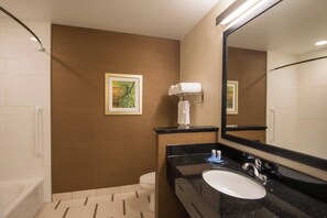 A bathroom with a white sink, black countertop, and a large mirror. There is a towel rack with a white towel and a framed picture on the wall. - Fairfield Inn & Suites Fort Wayne Southwest (Fort Wayne)