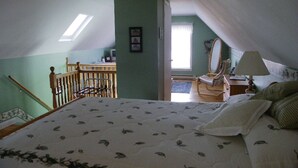 A bedroom with a bed, a chair, a desk, a mirror, and a lamp. - The Colonel's In B&B (Fredericton)