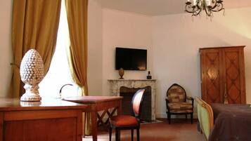 Una habitación con una mesa de madera, una silla, un televisor sobre la chimenea y un armario de madera.