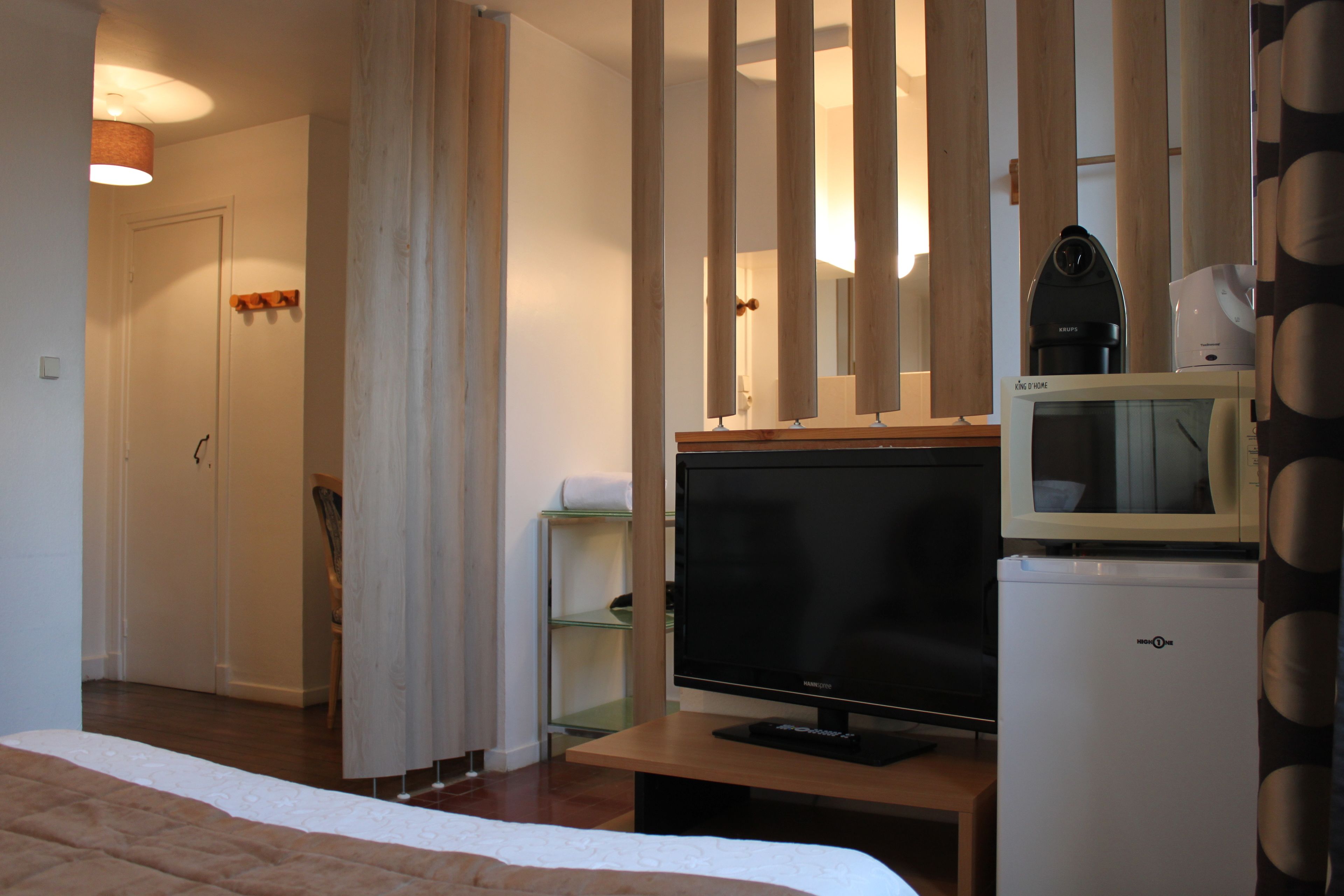 Ein Hotelzimmer mit einem Bett, einem Fernseher, einem Kühlschrank, einer Mikrowelle und einem Holzboden.