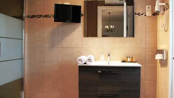 A modern bathroom with a dark wood vanity, a large mirror, and a mounted TV.