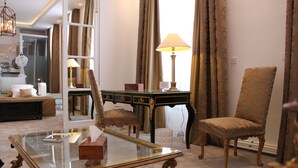 Una habitación con una mesa de vidrio, una silla de madera, un escritorio con cajones y una lámpara.