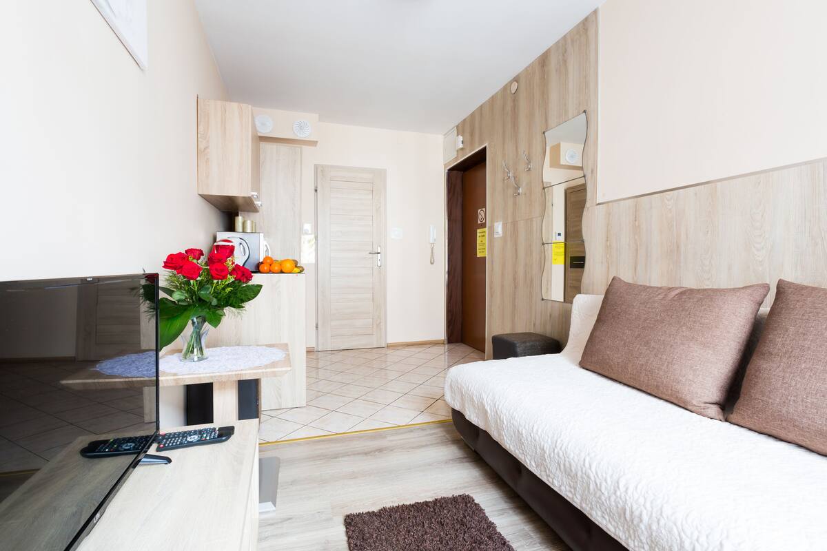 Una habitación de hotel moderna con una cama, un escritorio con un florero, un espejo y un armario.