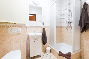 A bathroom with a sink, mirror, towel rack, shower, and toilet. - Aparthouse Apartamenty (Katowice)