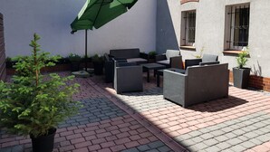 A patio with wicker furniture, a green umbrella, and potted plants. - Aparthouse Apartamenty (Katowice)