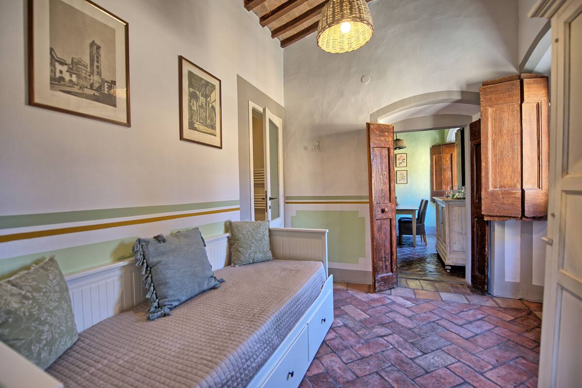 Quarto com cama, penteadeira e corredor que dá para uma sala de jantar.