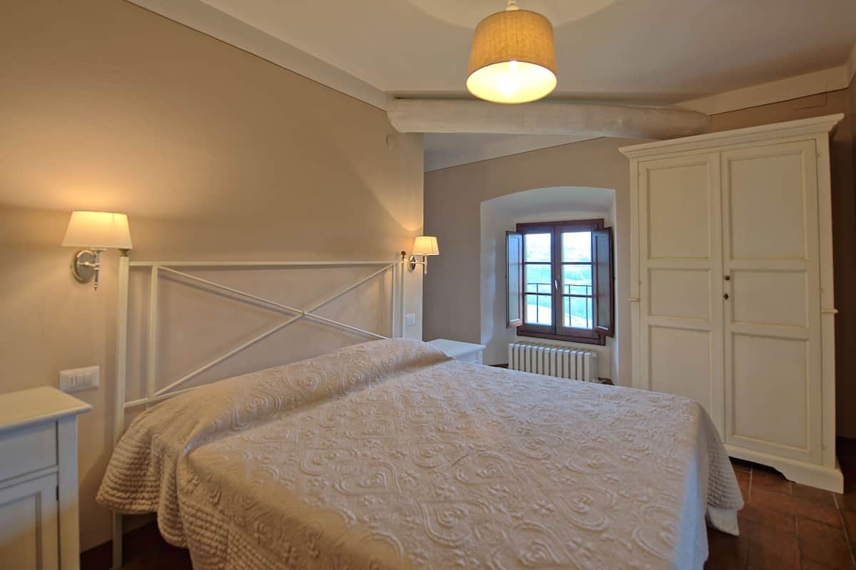 Um quarto com cama, guarda-roupa e janela com vista.