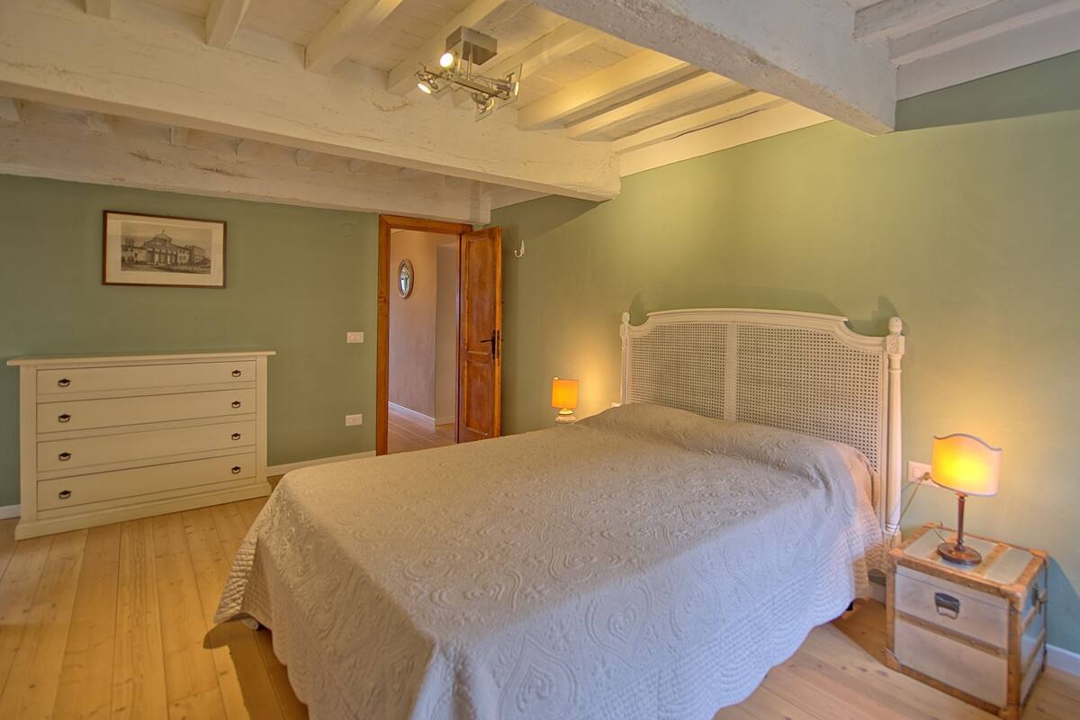 Quarto com cama, penteoude e mesa de cabeceira.