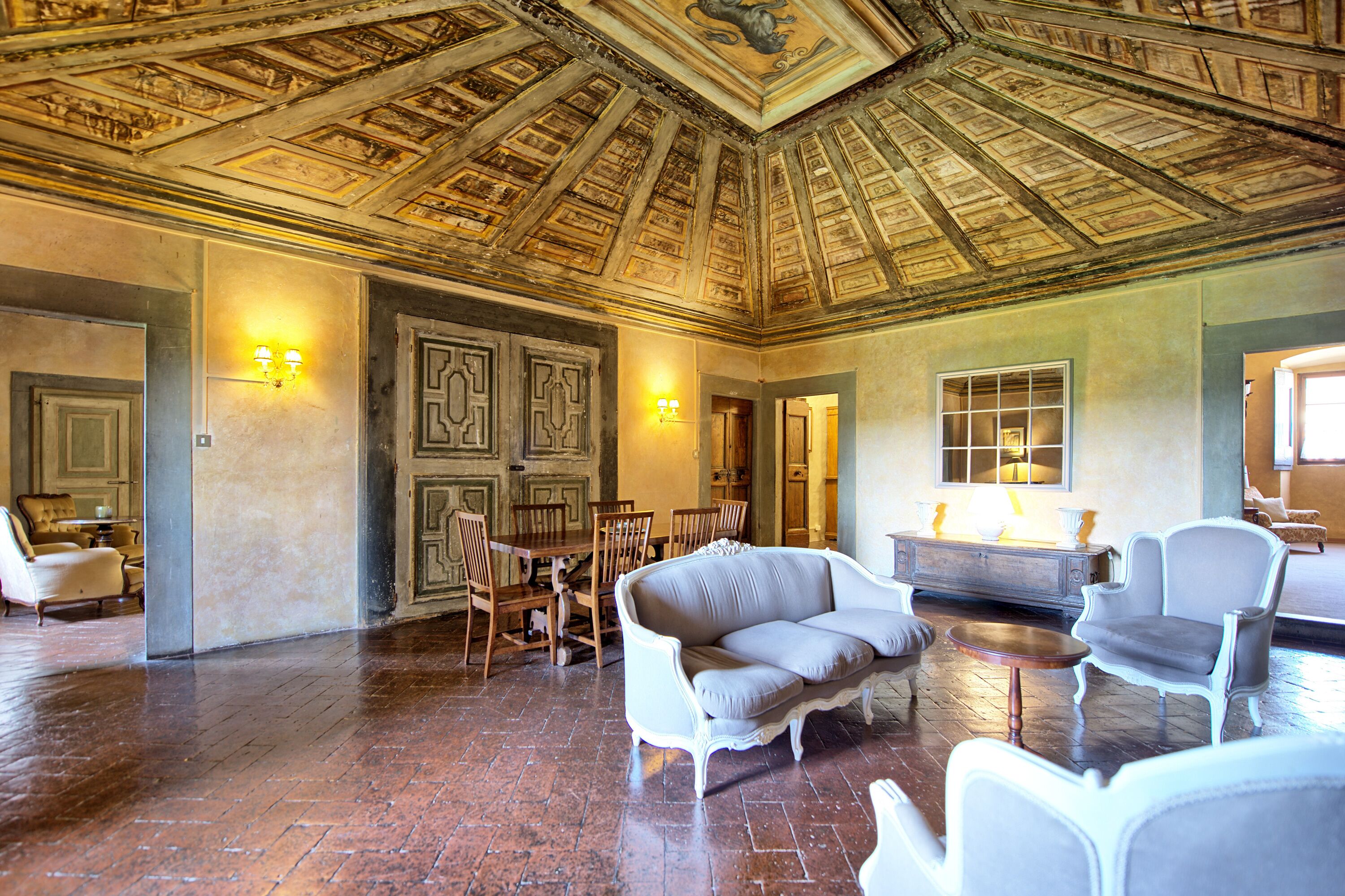 A spacious room with a high ceiling, wooden flooring, and a seating area with a sofa and chairs.