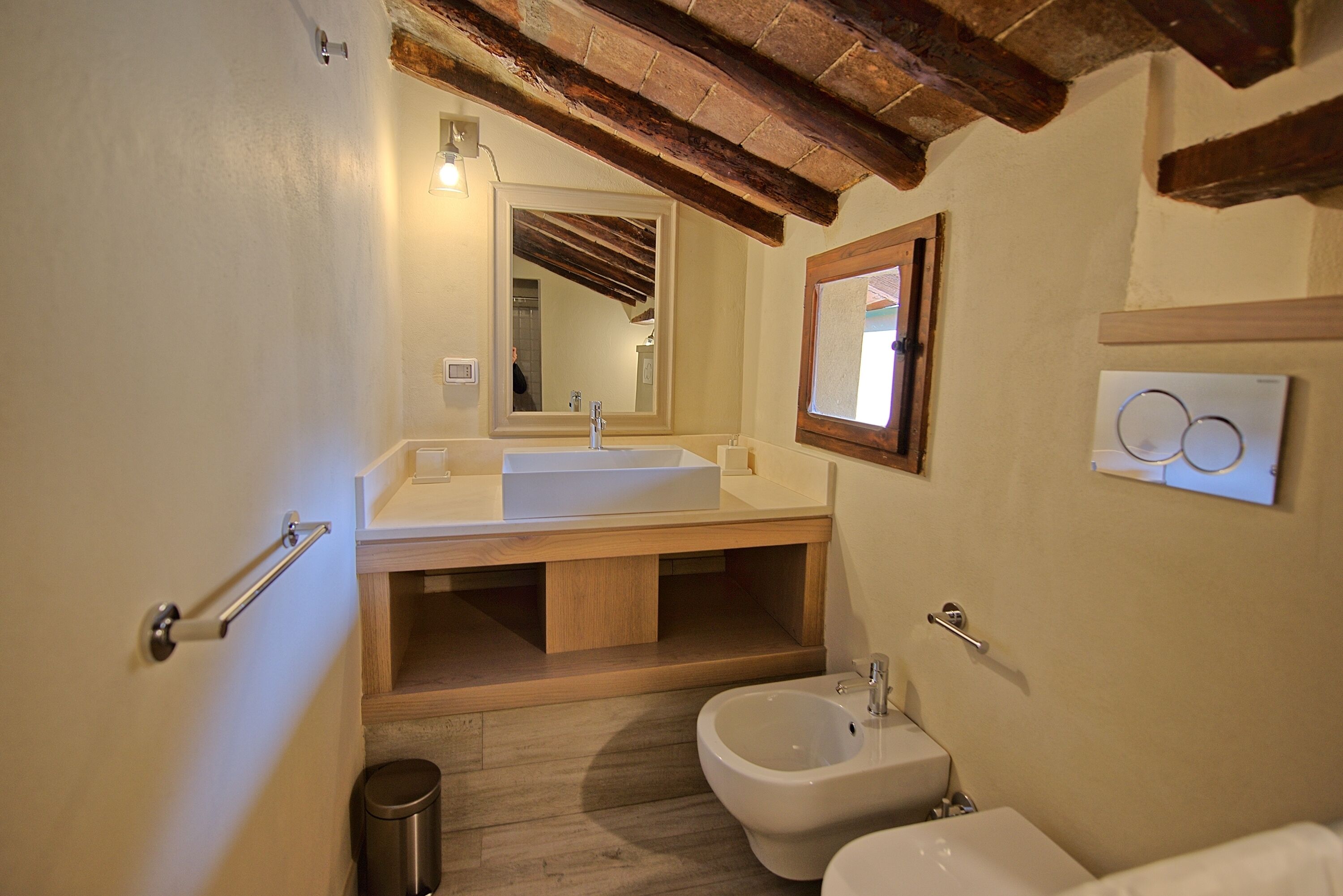 A bathroom with a wooden vanity, a large mirror, a bidet, and a toilet.