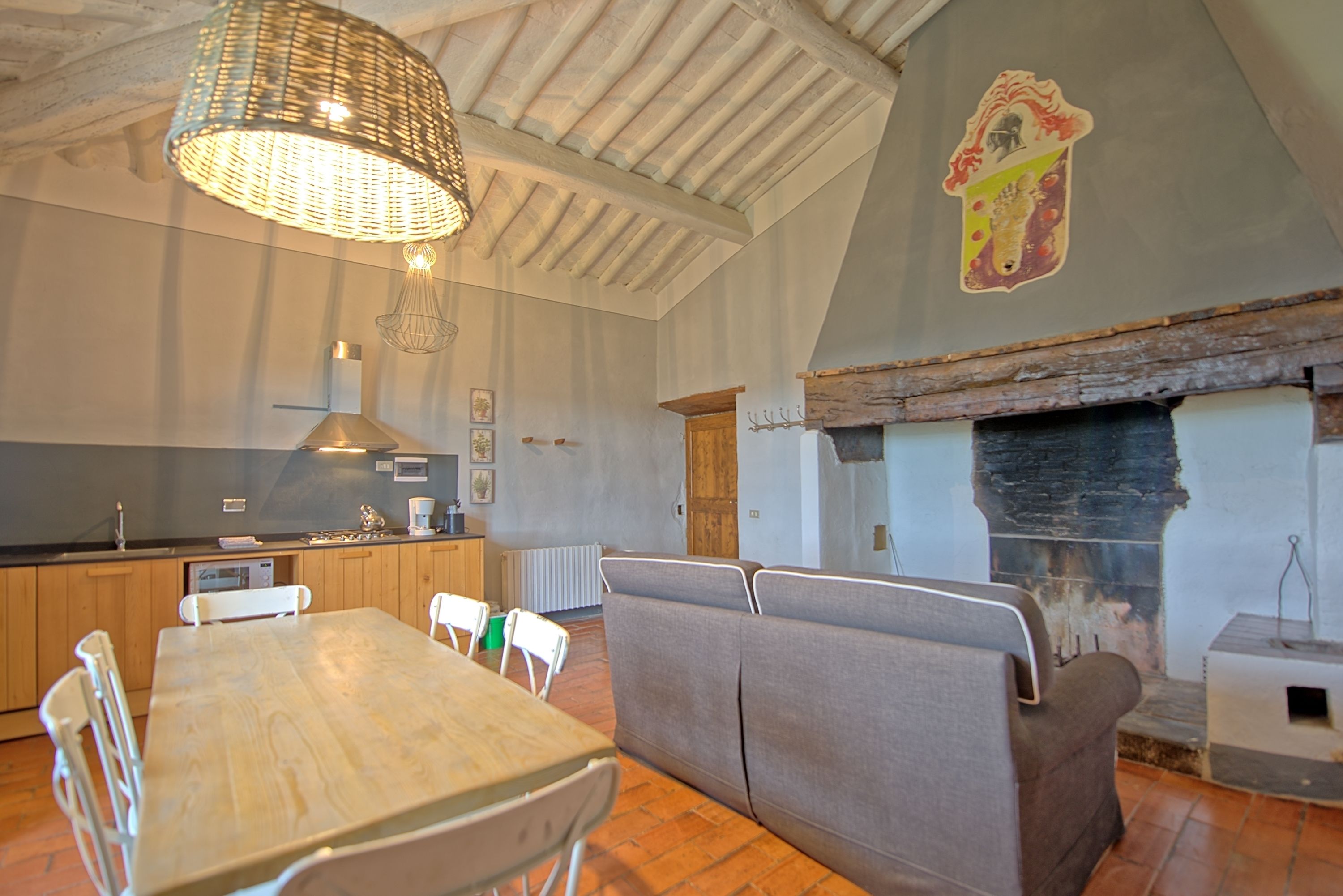 Une cuisine chaleureuse avec des meubles de rangement en bois, une table à manger avec des chaises, un canapé et une cheminée.