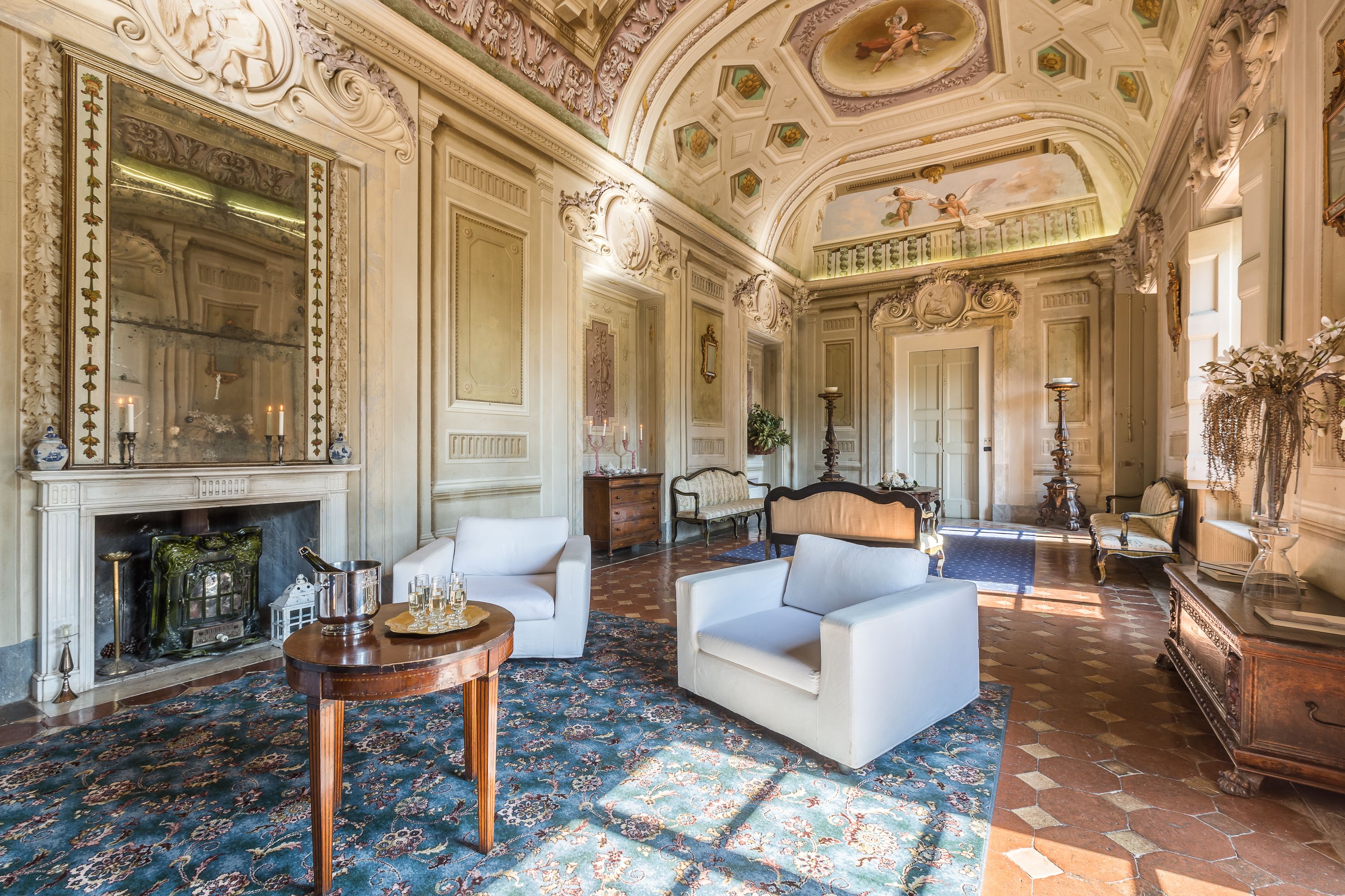 A grand room with ornate ceilings, a fireplace, and a large mirror.