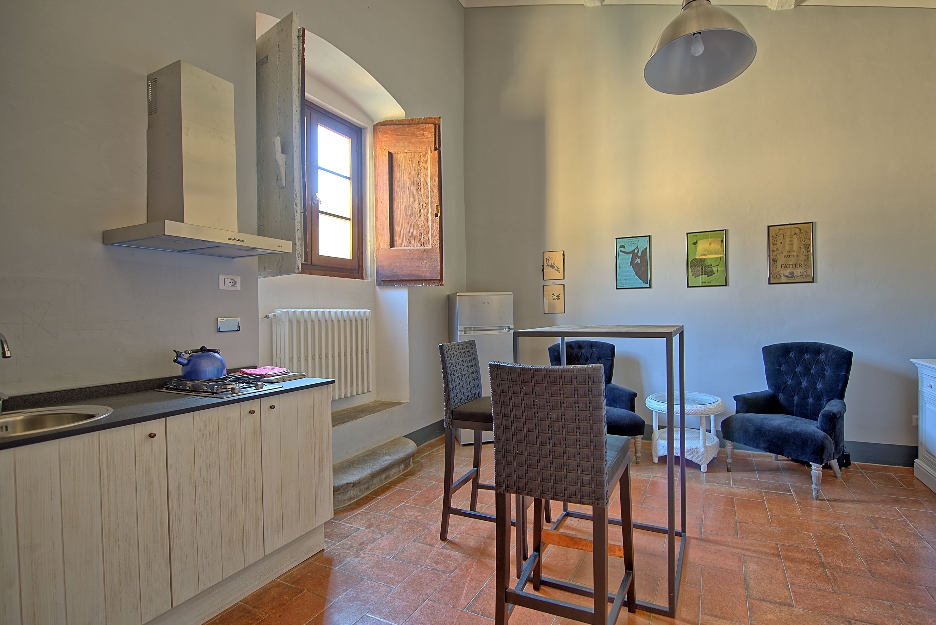 Une cuisine équipée d’une cuisinière intégrée, d’une fenêtre et d’un coin repas avec des chaises et une table.