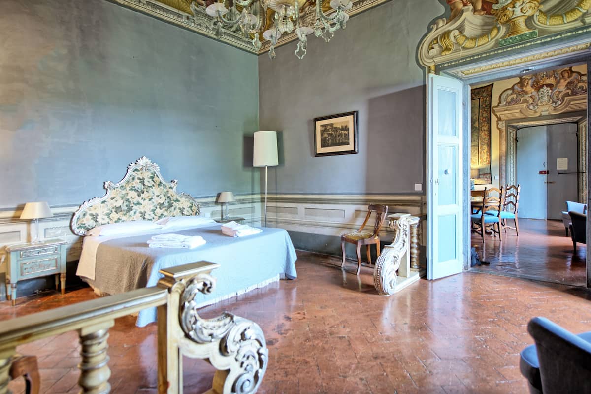 Quarto com uma cama grande, um candelabro e mobiliário decorado.