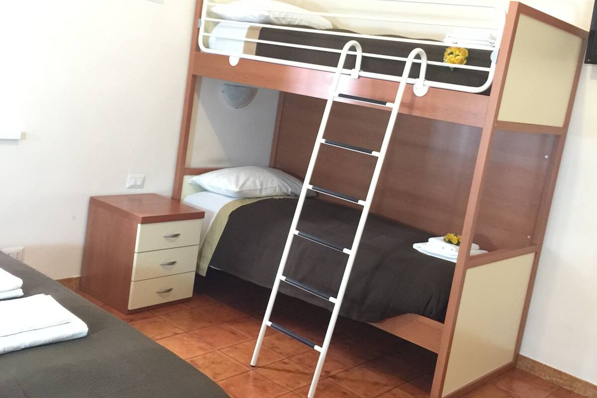 A bunk bed with a ladder, a small bedside table, and a chair.
